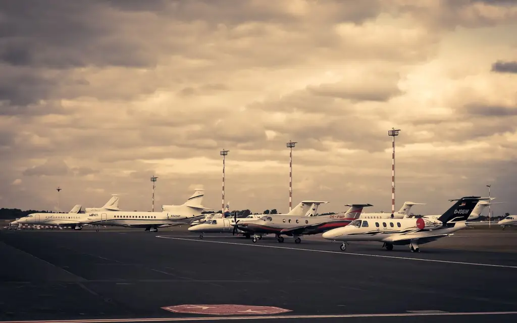 Line of private jets parked on the tarmac under a dramatic cloudy sky, showcasing aviation and travel