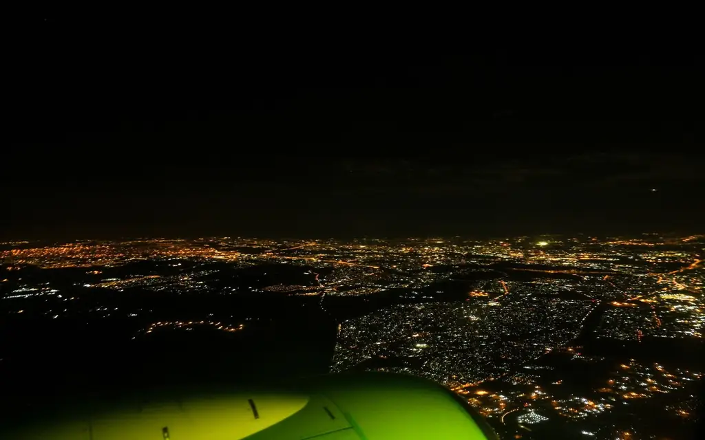 Dramatic aerial view of a city at night, captured from an airplane in flight